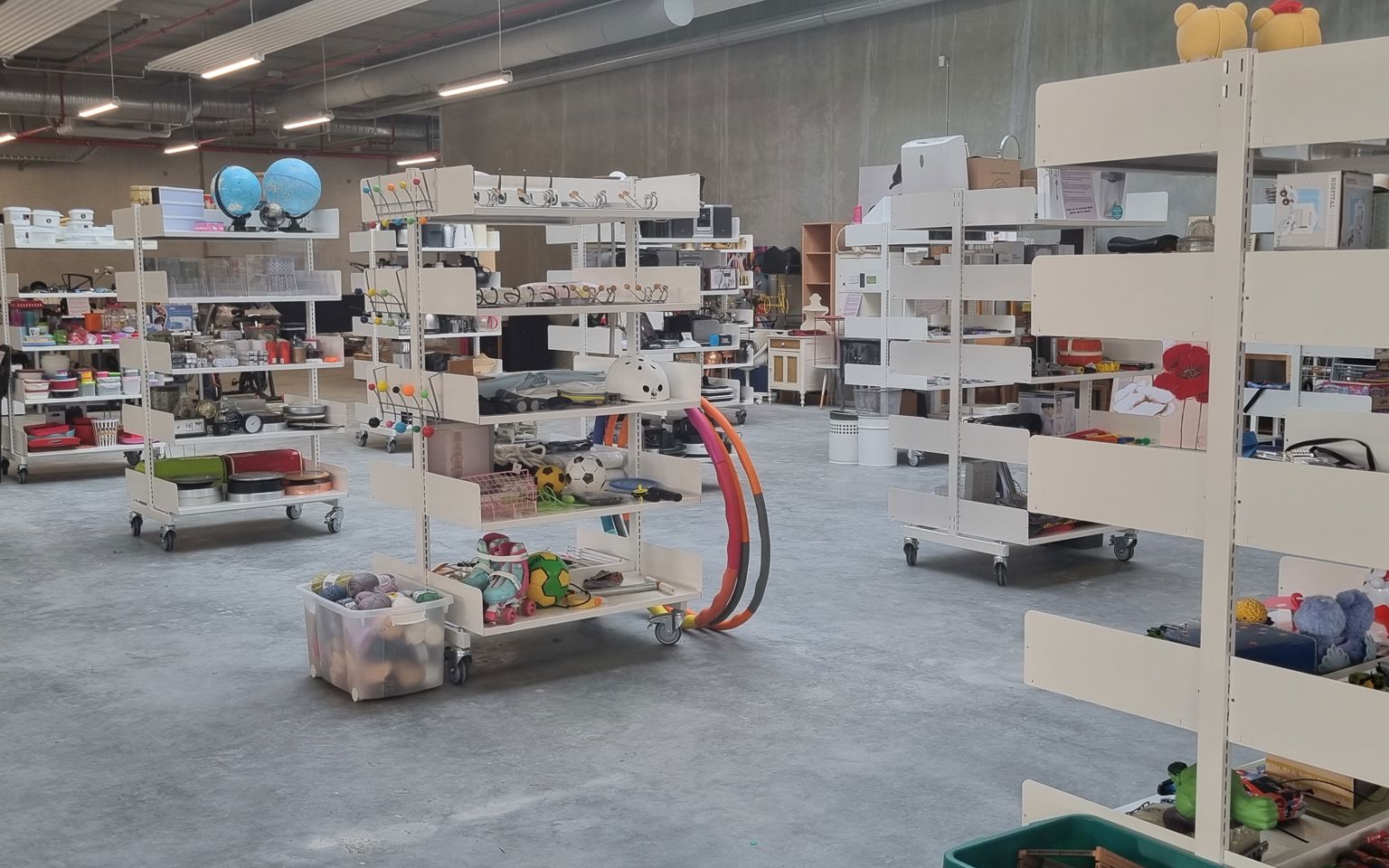Foto af genbrugsbutikken på RessourceCenter Vejle. Rummet er fyldt med hylder, der indeholder forskellige genbrugsvarer som køkkenudstyr, legetøj, bøger og andre brugte effekter, der er gratis for borgere at tage med hjem