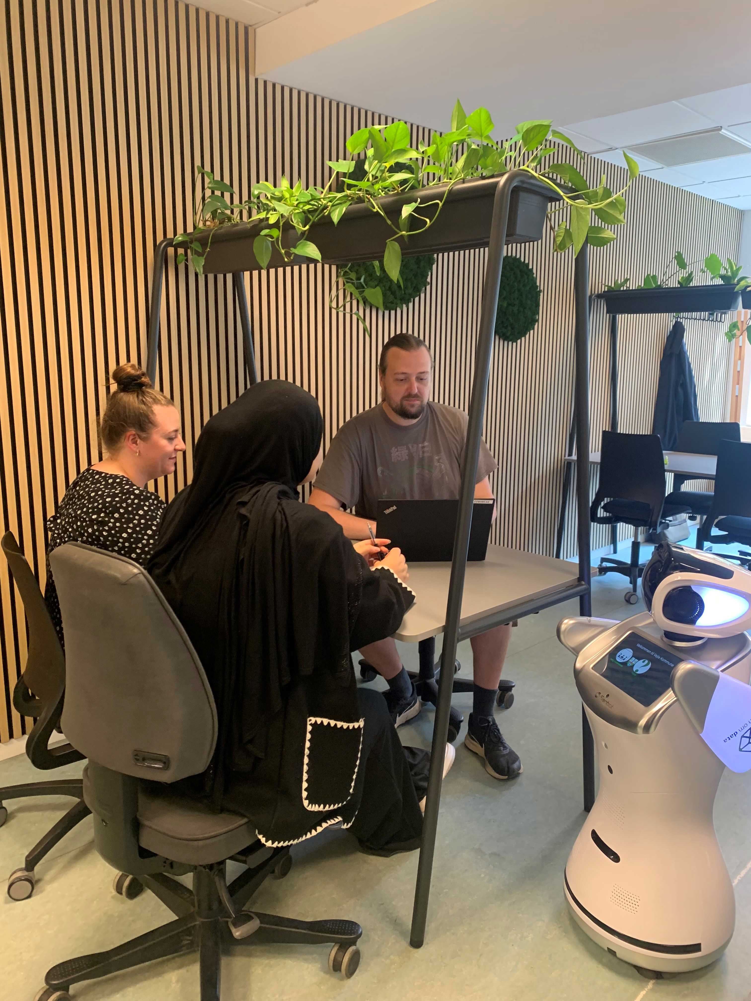 3 elever har gruppearbejde på deres skoleophold på Campus Vejle siddende ved et bord