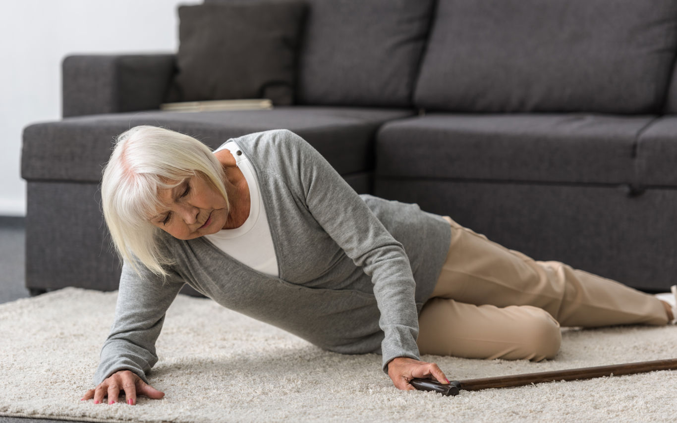 Ældre kvinde liggende på gulvet på et gulvtæppe
