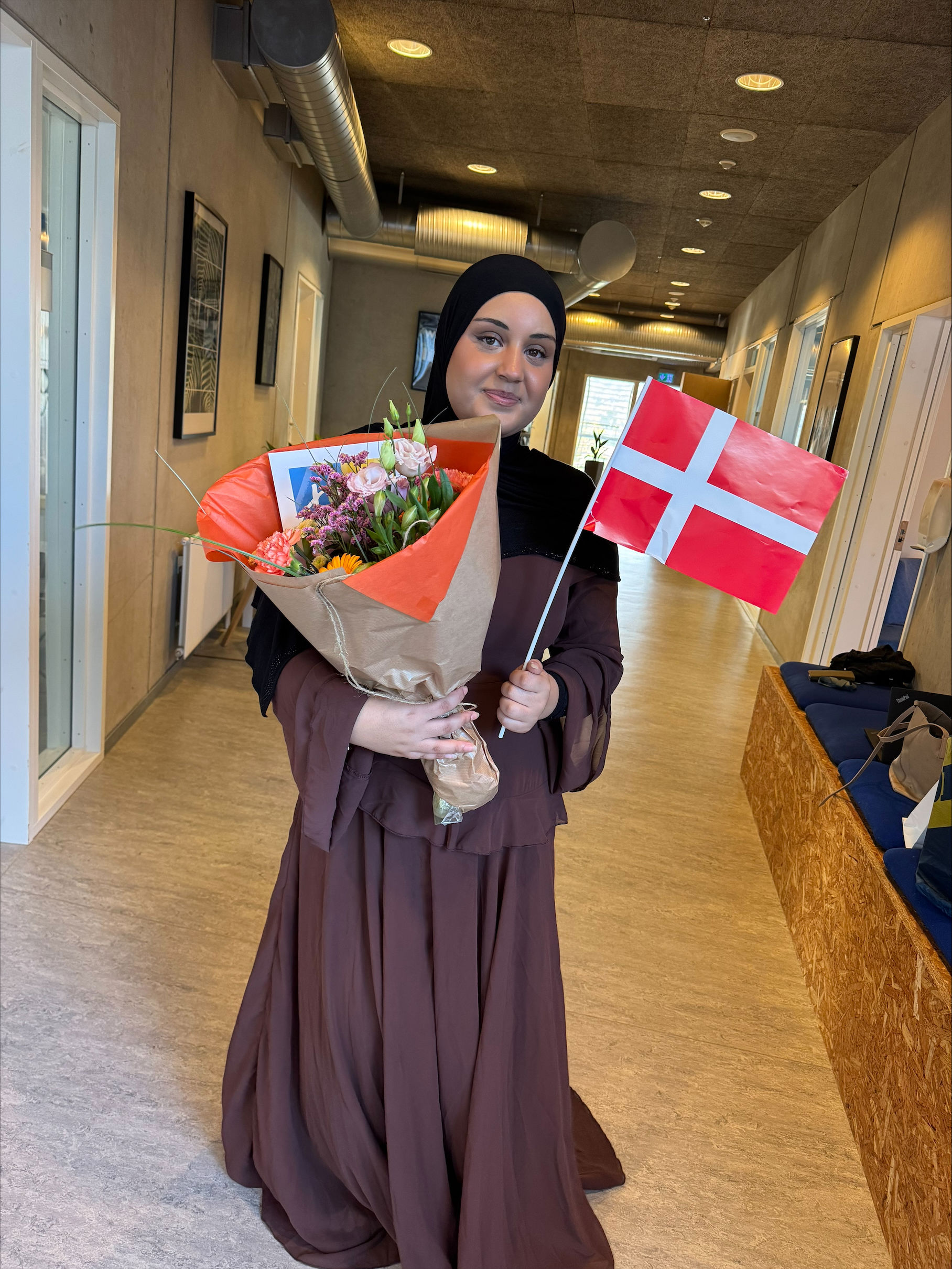 Fejring efter fagprøveeksamen juni 2026 på Campus Vejle - man ser Aja med blomst og flag