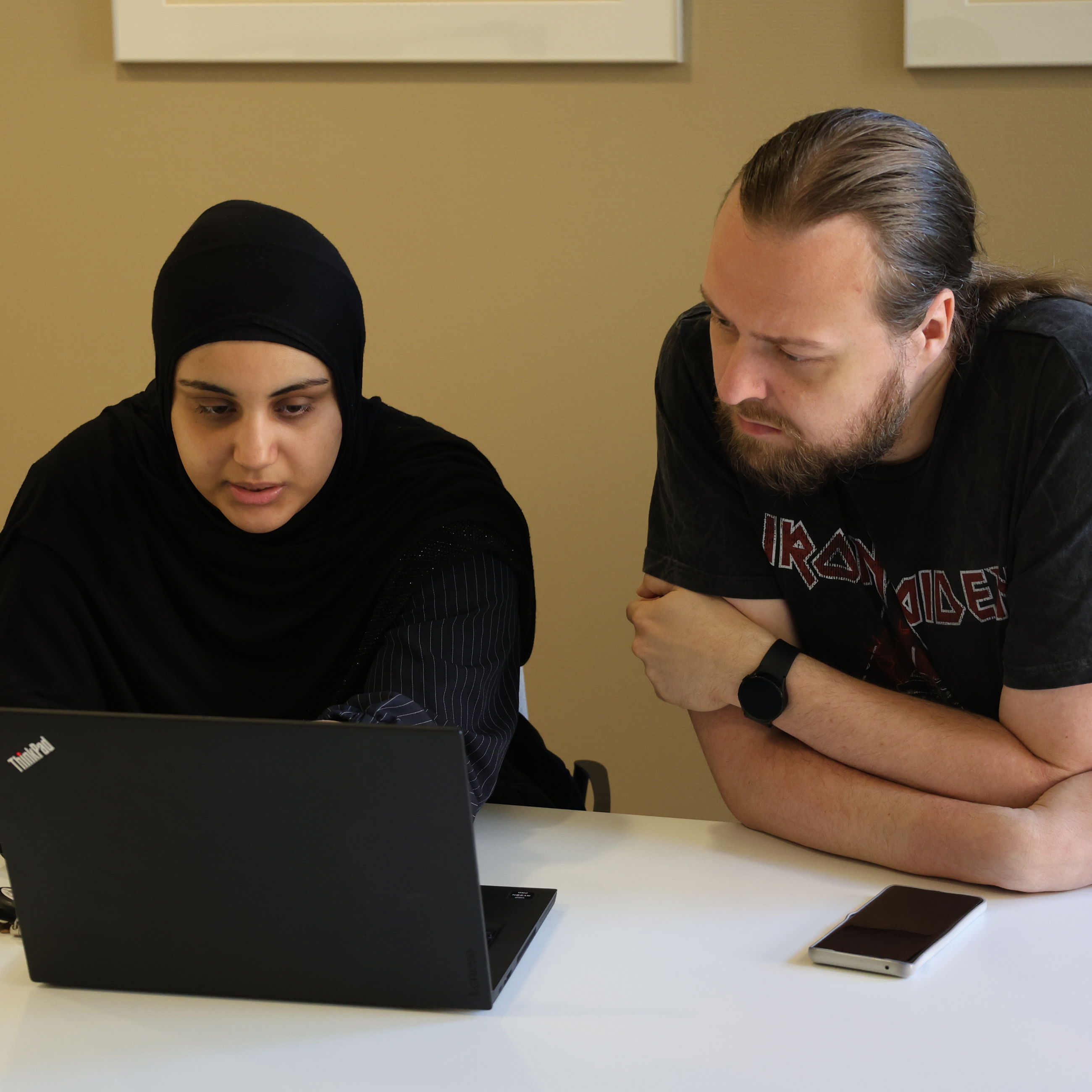 Kontoreleverne Aja og Mark arbejder koncentreret foran PC