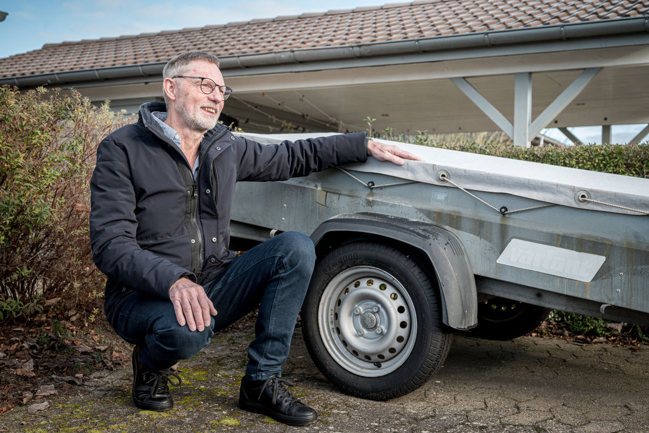 Allan Jensen fra Bredballe sidder på hug foran anhænger på det lille vænges fælles parkeringsplads.