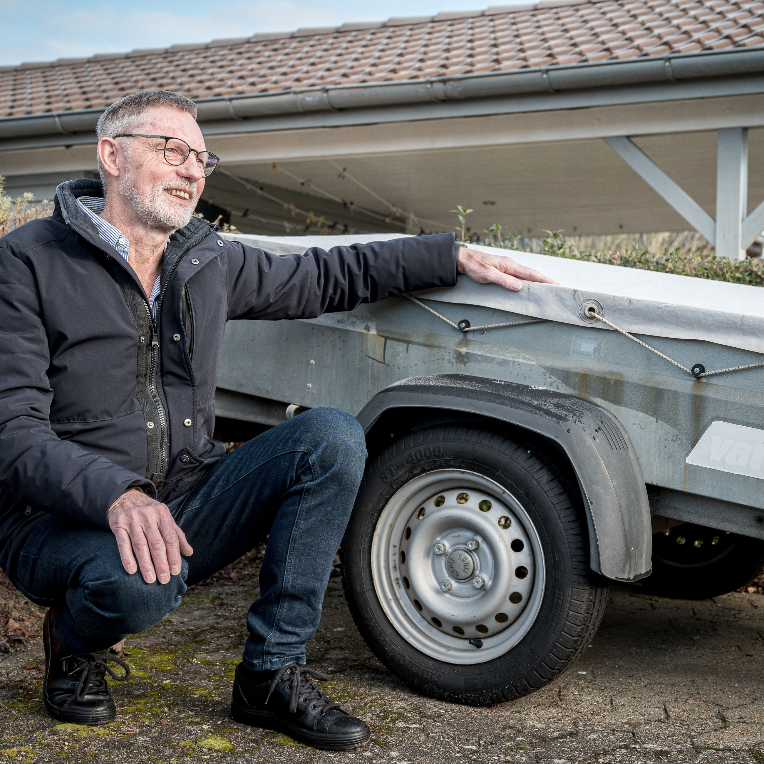Allan Jensen fra Bredballe sidder på hug foran anhænger på det lille vænges fælles parkeringsplads.