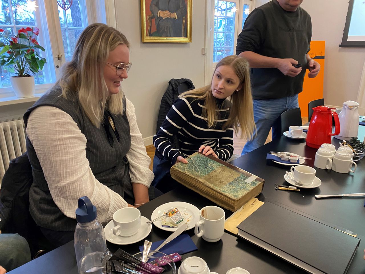 Signe og Frida med en gammel protokol fra besøg på Stadsarkivet