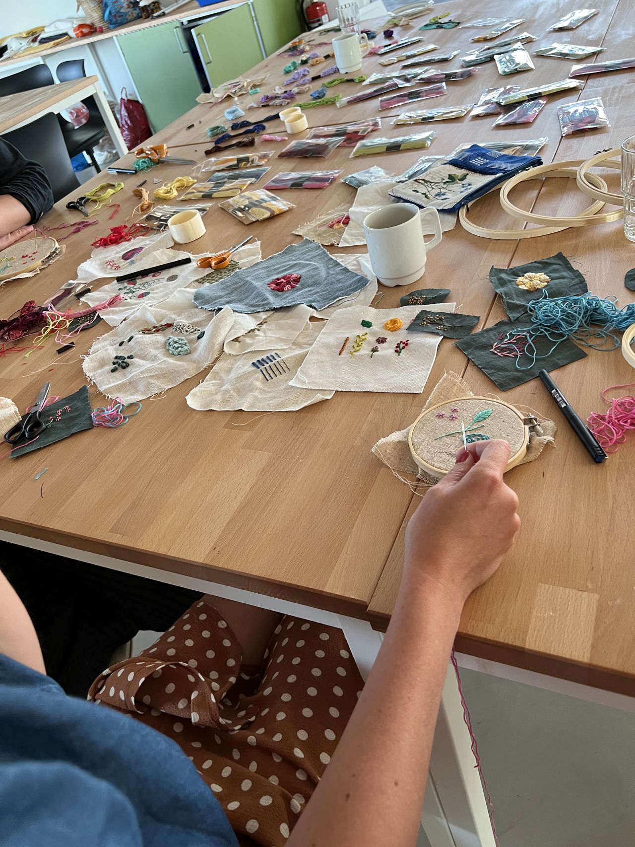 Workshop med broderi – bord fyldt med stofstykker, tråd og håndarbejde i gang.