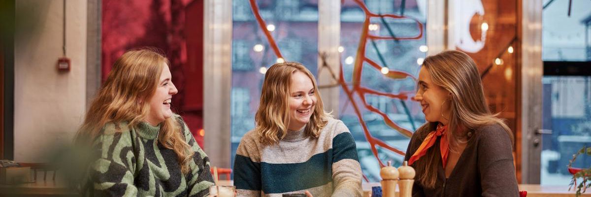 Tre kvinder drikker kaffe sammen i Spinderihallerne.