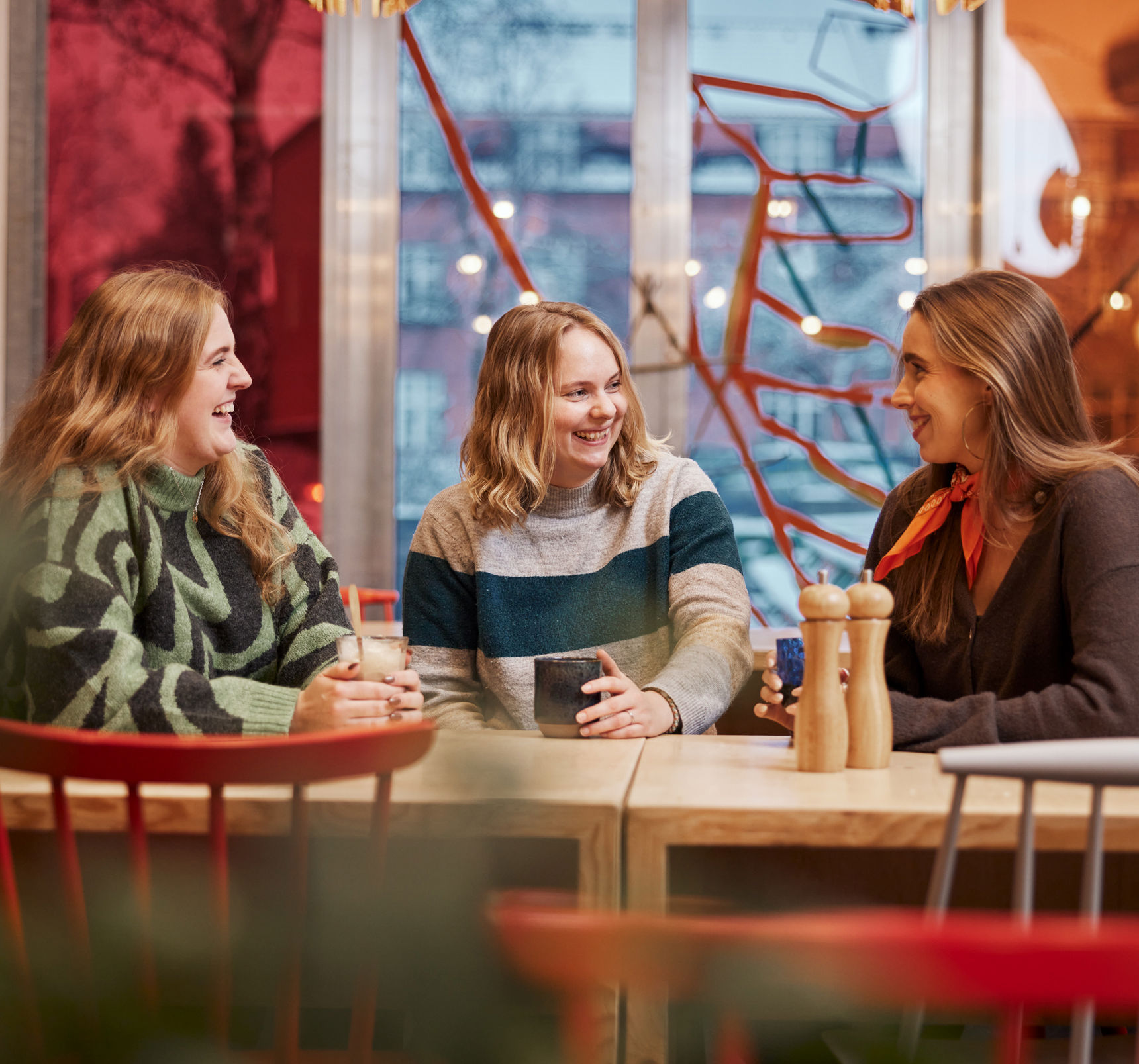 Foto af unge siddende ved et bord med kaffe/the i hænderne