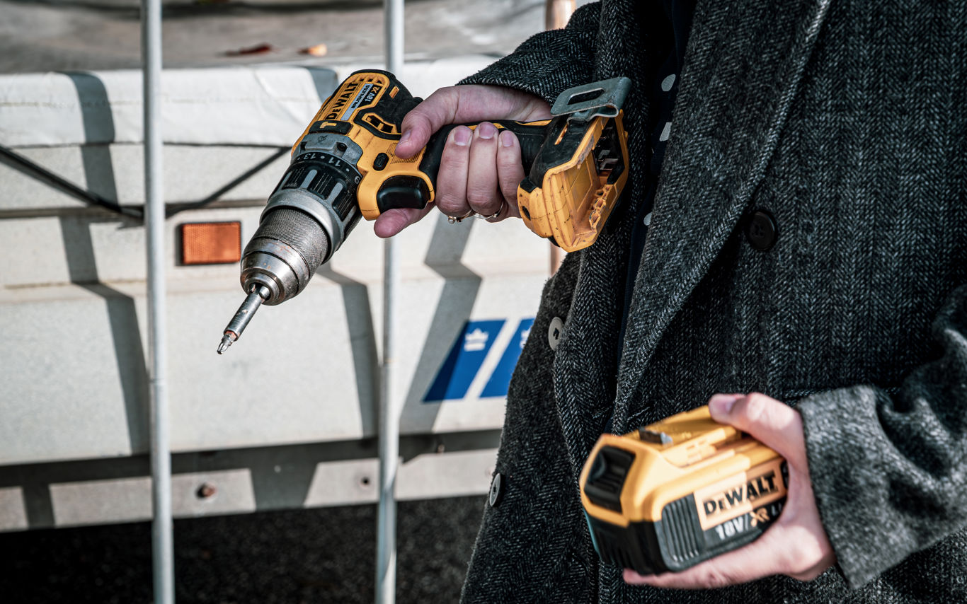 Nærbillede af en person, der holder en boremaskine og batteri.