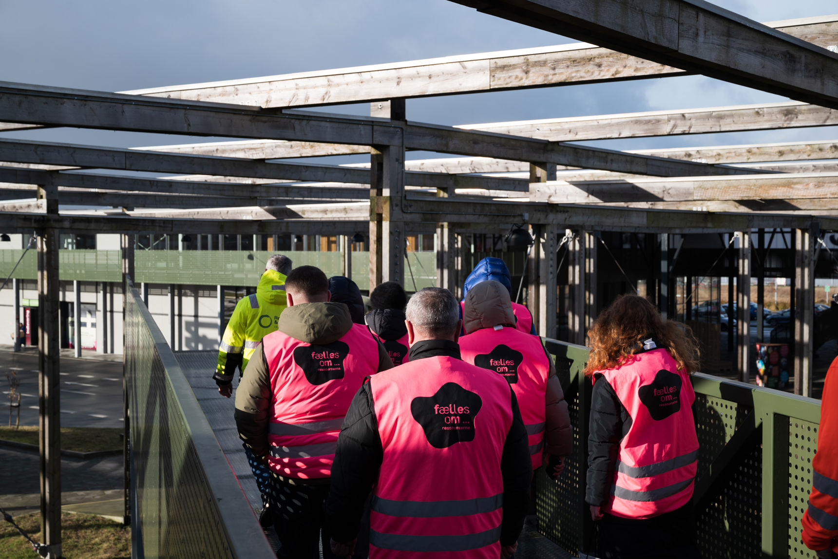 En gruppe mennesker iført pink sikkerhedsveste ses bagfra, mens de går rundt på Læringsbroen på RCV.