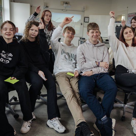 Unge der rækker hånden op i klasseværelse