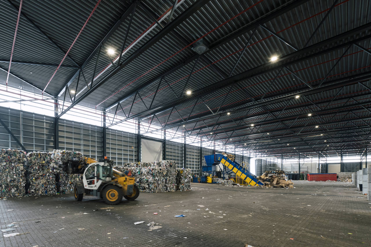 Indvendig hal med affaldshåndtering på RessourceCenter Vejle. Stor industrihal med maskiner og affald i forskellige fraktioner.