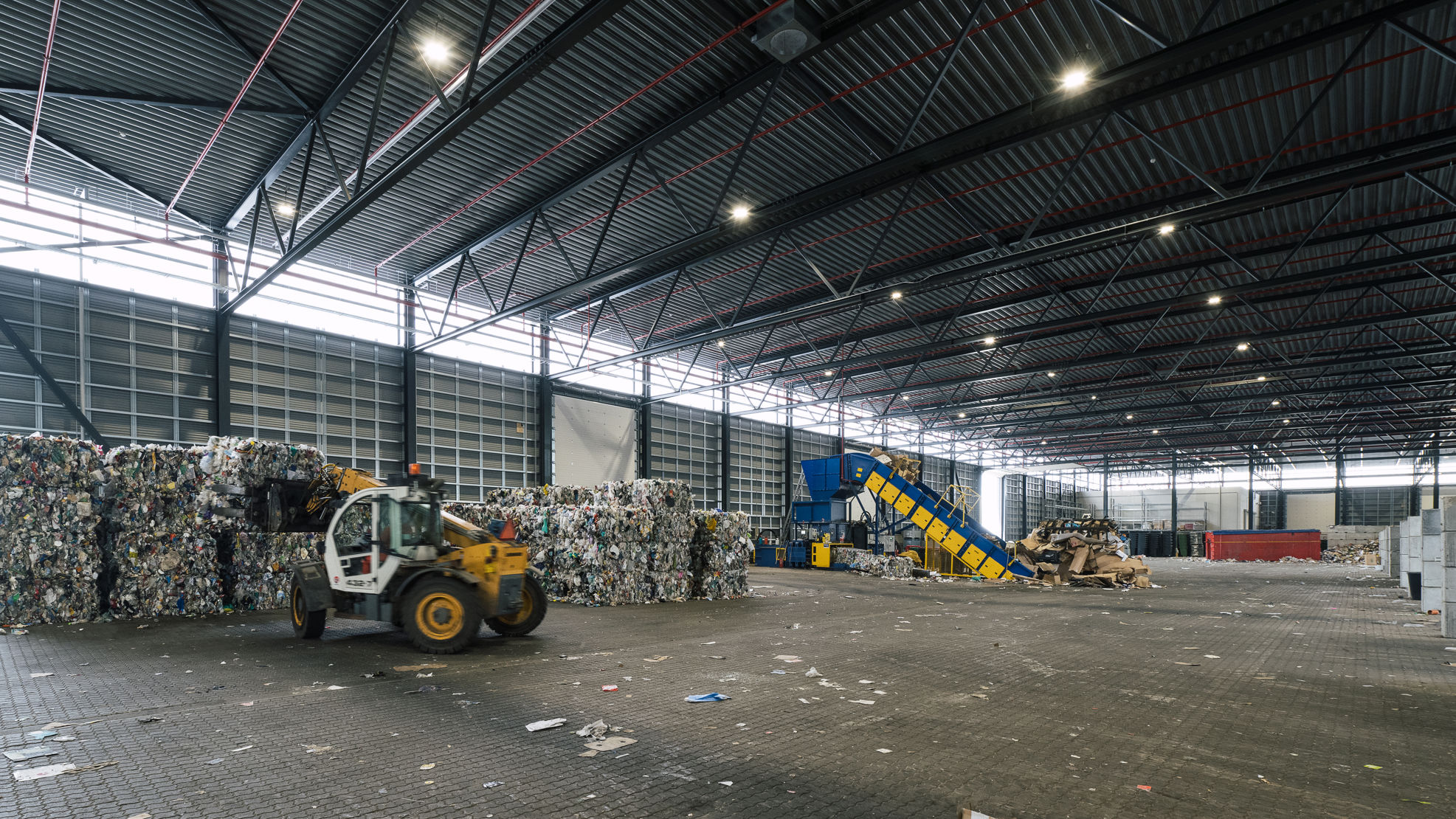 Indvendig hal med affaldshåndtering på RessourceCenter Vejle. Stor industrihal med maskiner og affald i forskellige fraktioner.