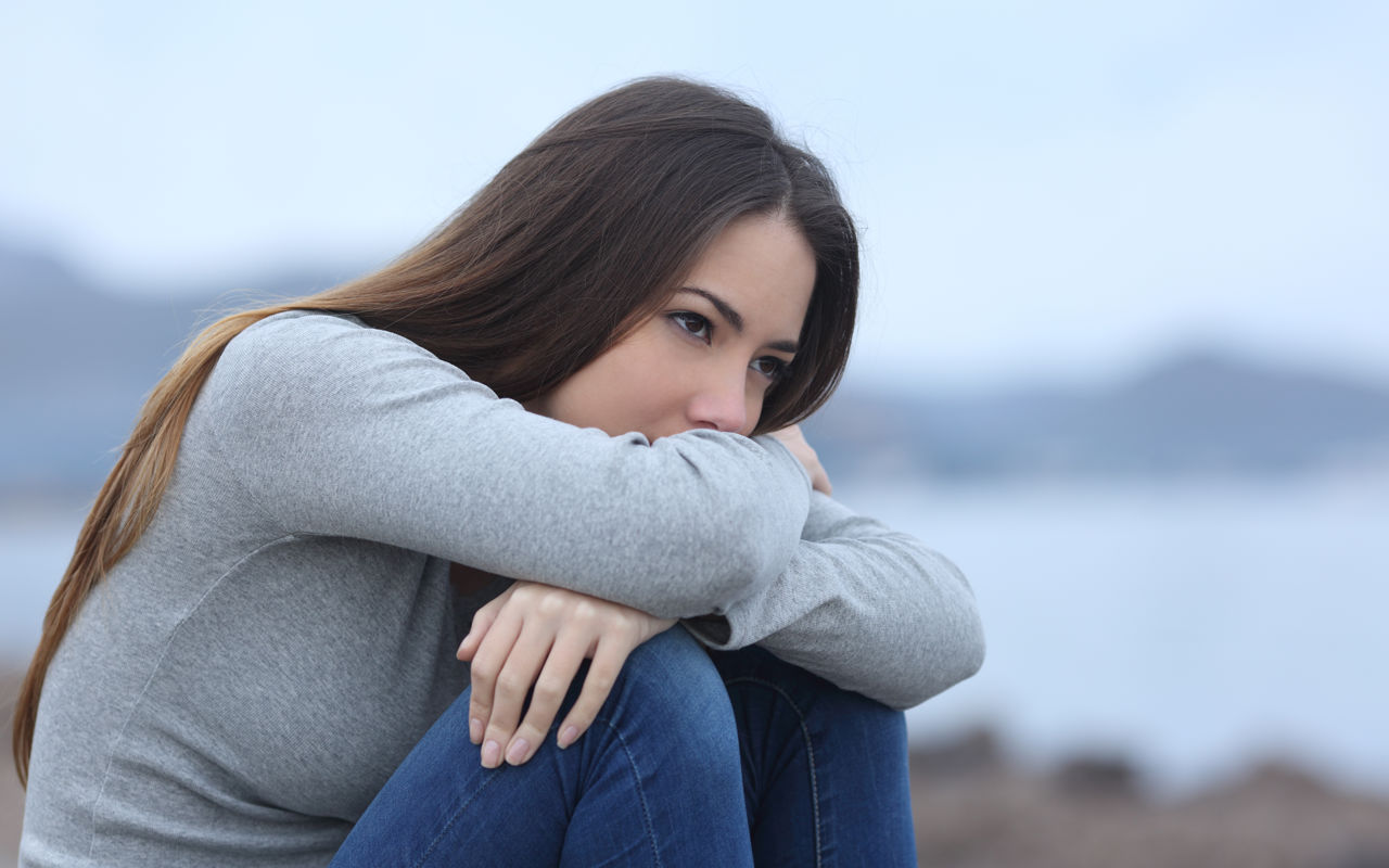 Foto af ung pige der sidder på hug med foldede arme