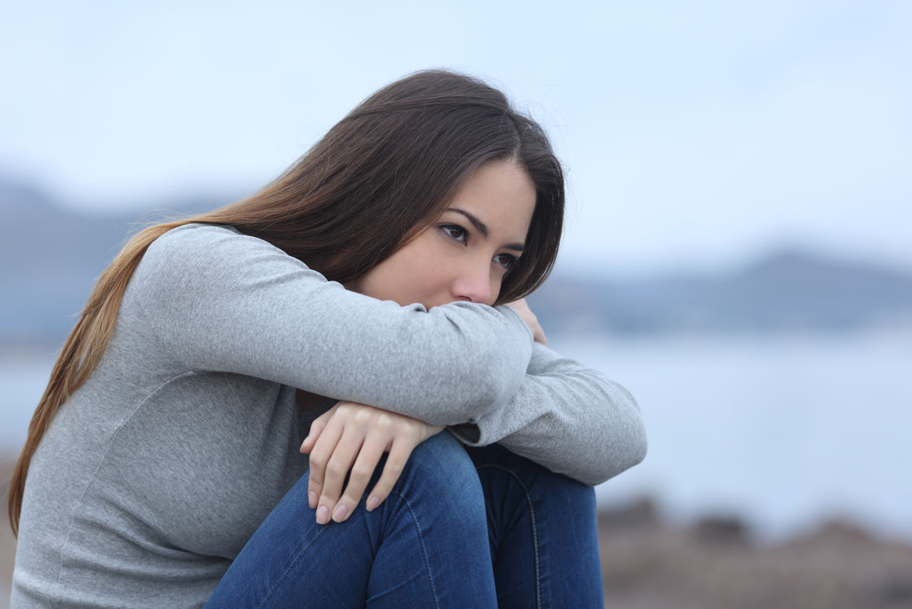 Foto af ung pige der sidder på hug med foldede arme