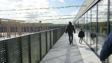 En voksen og et barn ses bagfra, mens de går rundt på Læringsbroen på RCV.