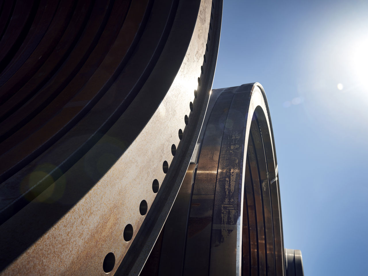 Vindemølledele på Welcon. Industridele, i baggrunden ses himlen og lidt sol.