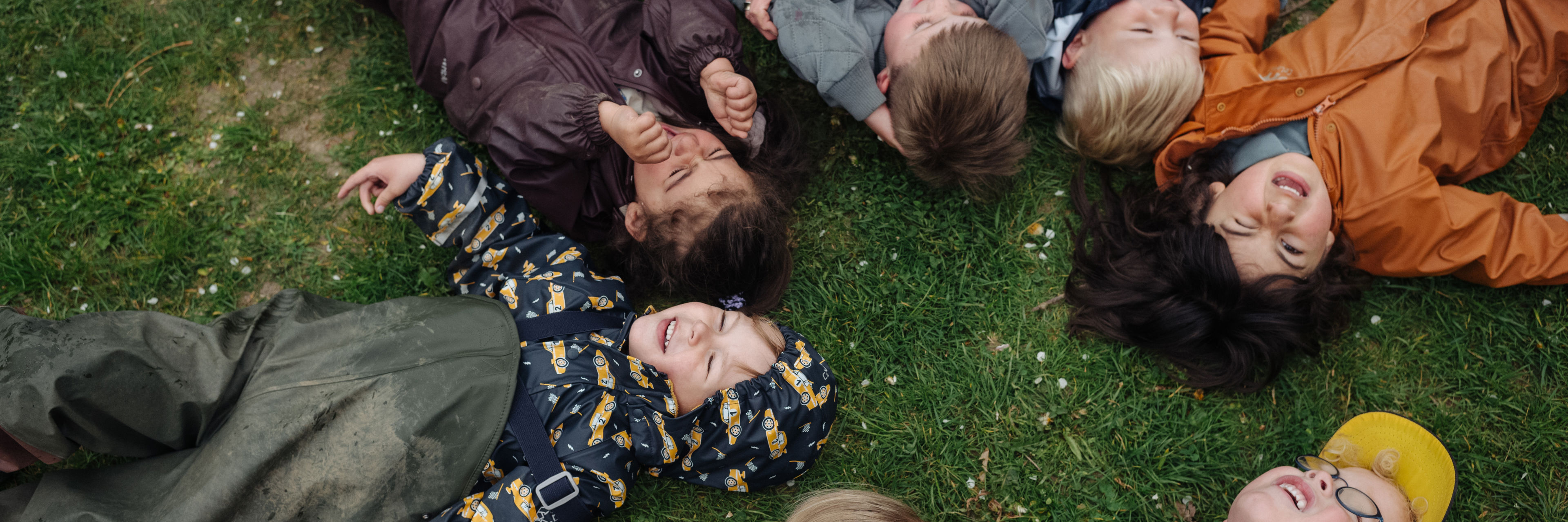 børn ligger på ryggen på græsset