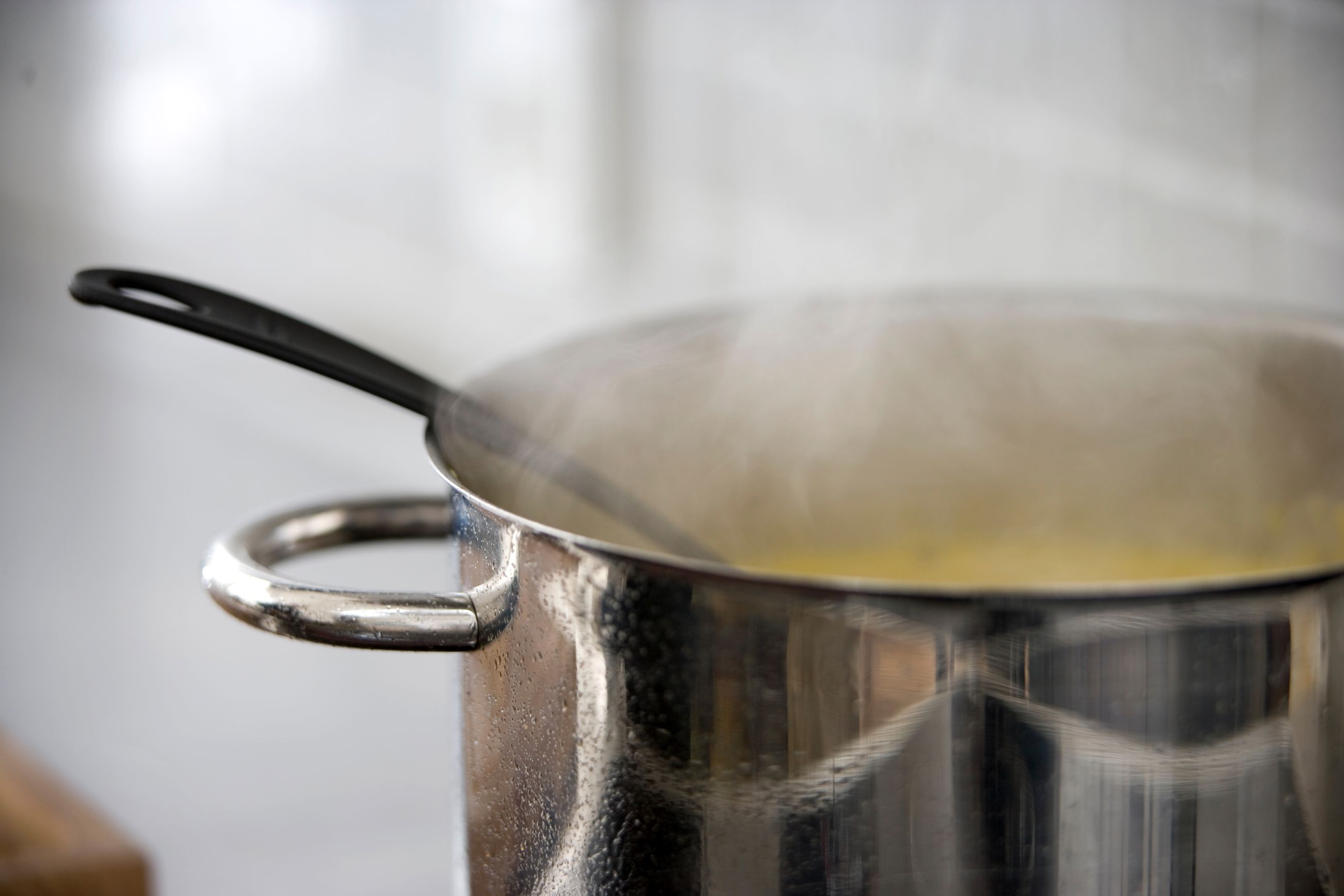 Gryde på komfur med varmt indhold, der damper.
